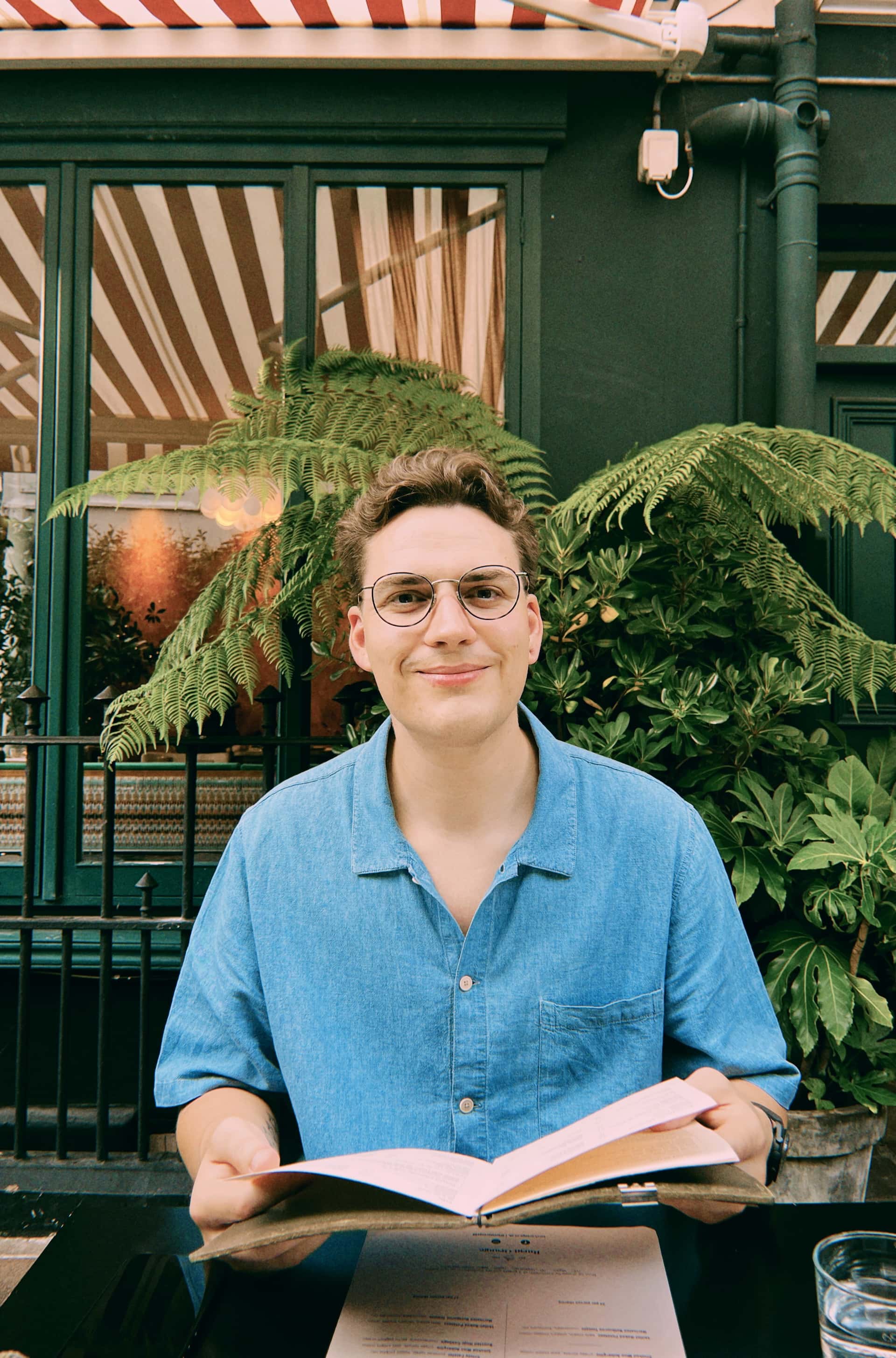 Sam Goddard sat outside a restaurant, holding a menu